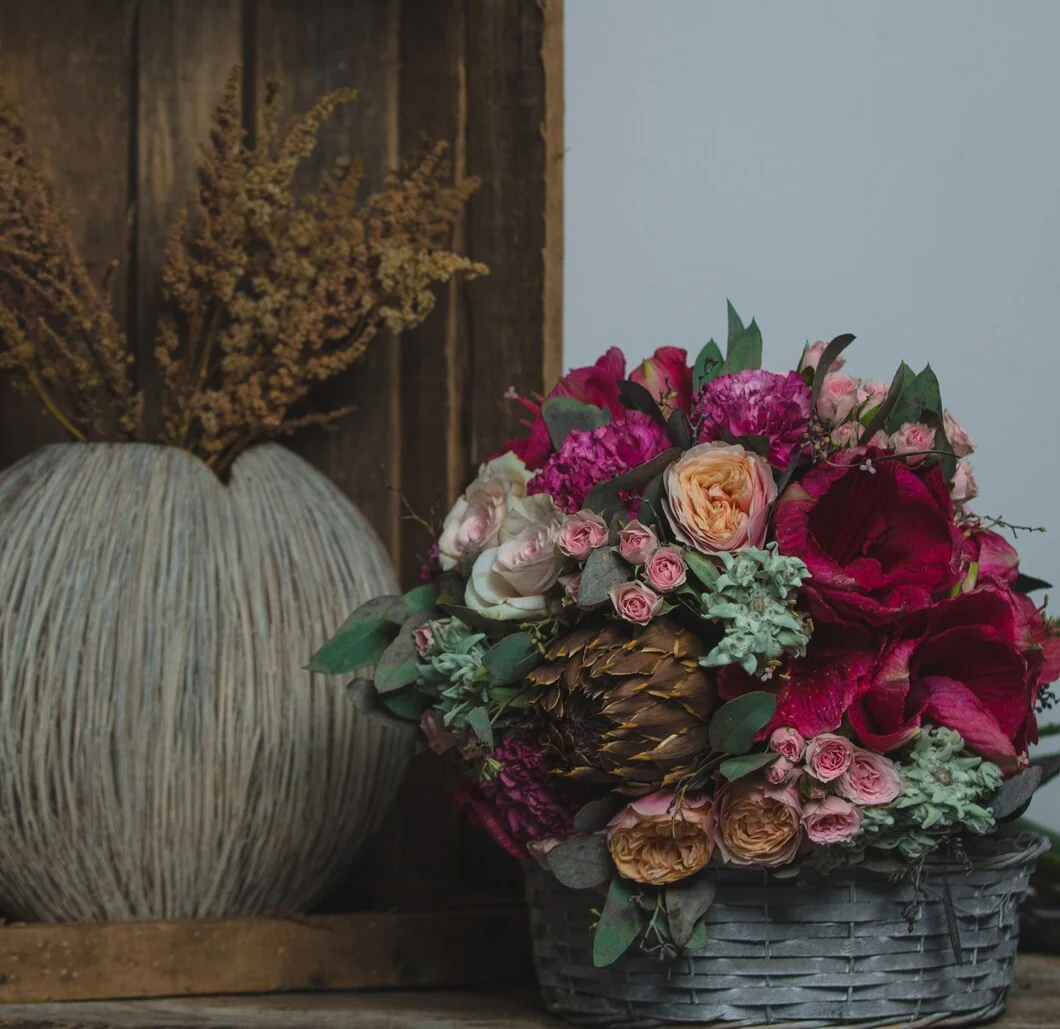 Dark basket with rich pink and burgundy floral arrangement