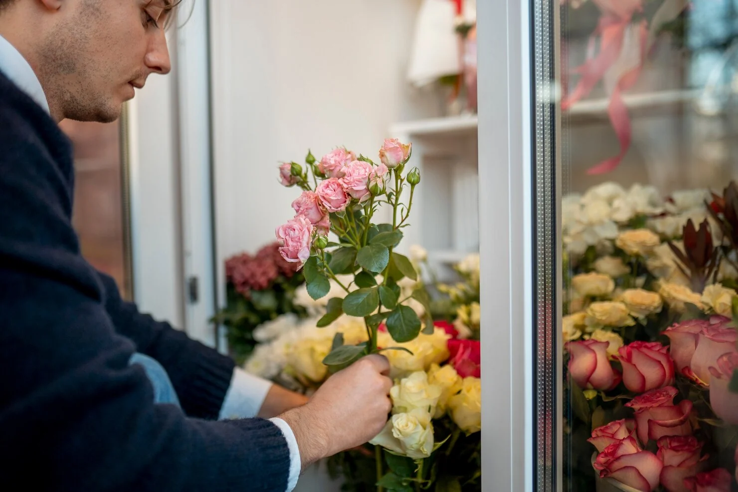 Hands selecting roses from a stocked floral display