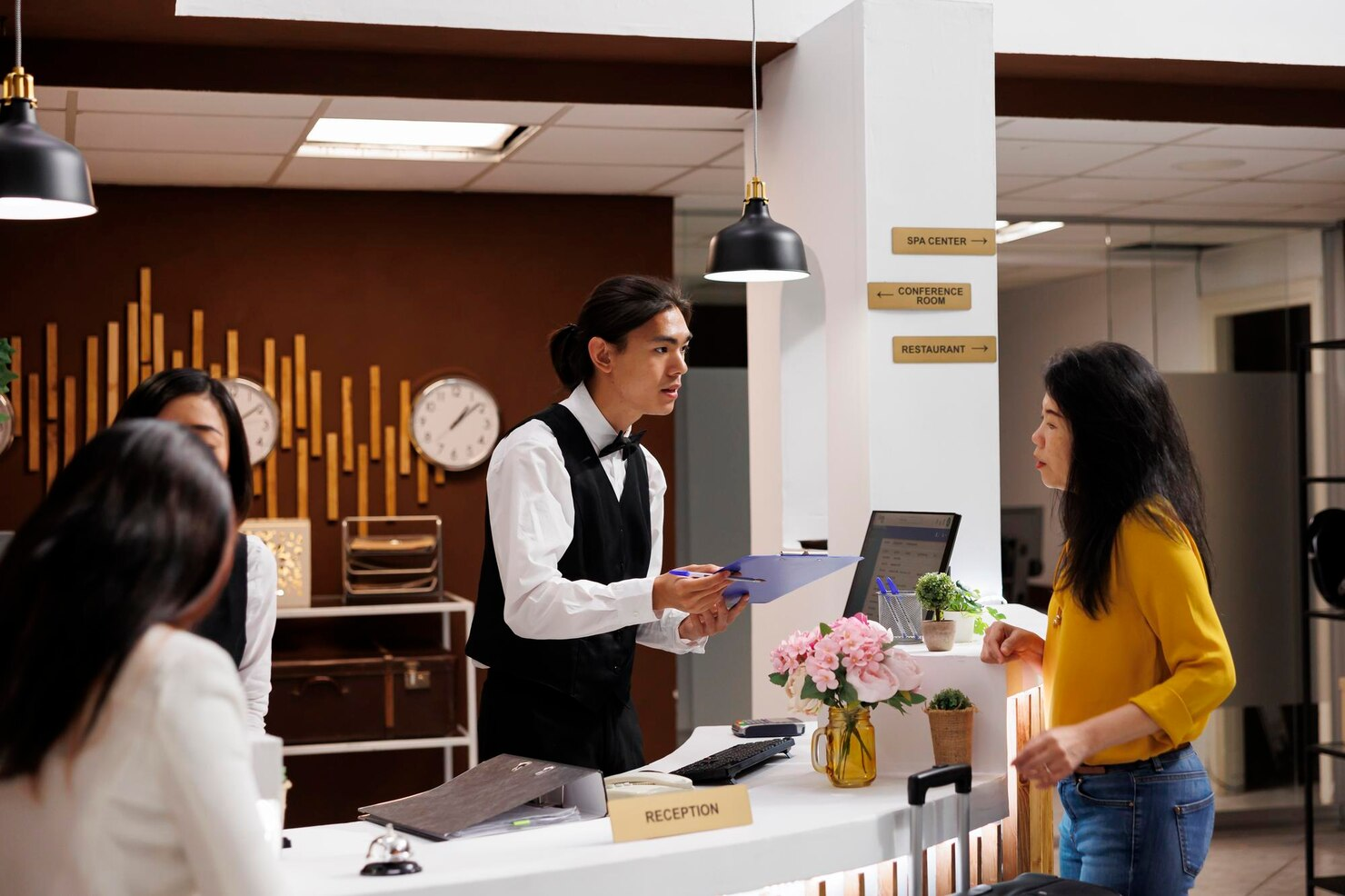 Hotel concierge assisting guests at reception with flowers nearby